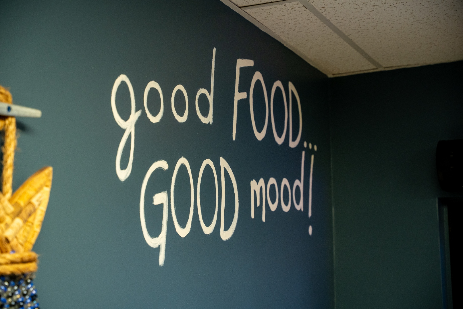 &lsquo;Good Food... GOOD Mood!&rsquo; mural painted on navy wall at Luc's Seafood & Grill